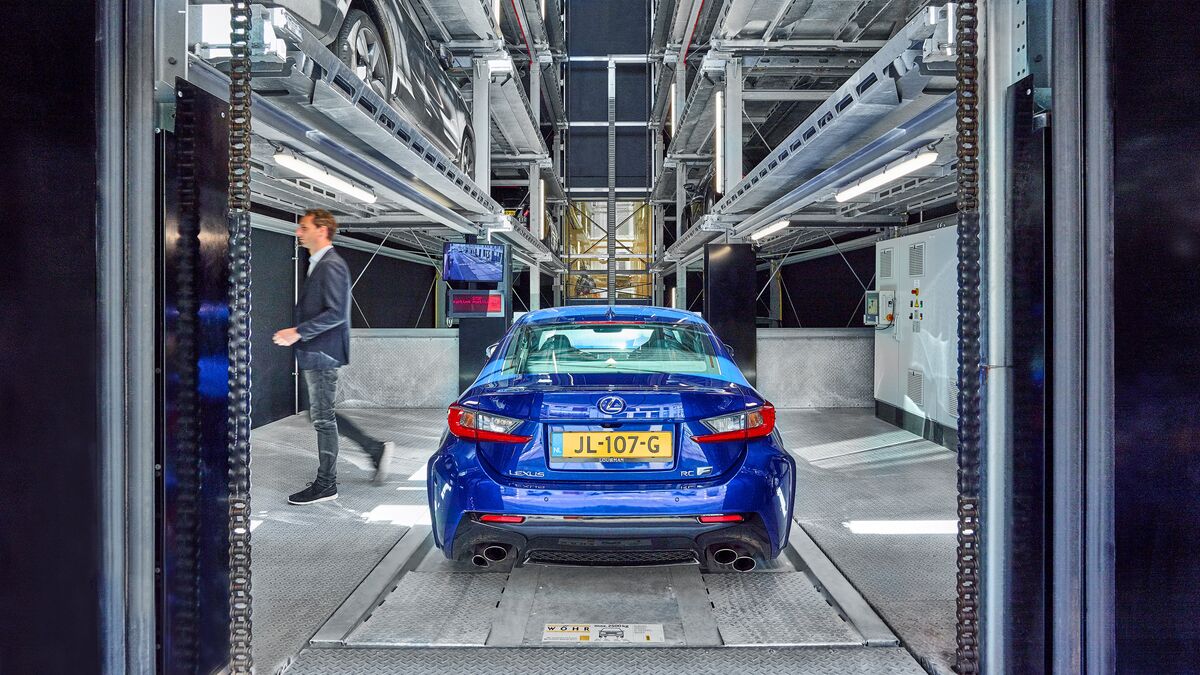 Une voiture bleue se trouve dans la cabine d'entrée d'un système de stationnement
