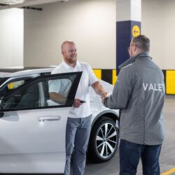 The image shows the vehicle handover in an automated parking system, where the vehicle key is handed over to the user after the vehicle has been retrieved from the parking system.
