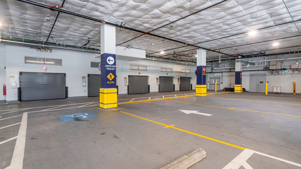 The image shows the entrance to an automated parking system in a modern underground garage with several access gates.