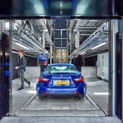 Une voiture bleue se trouve dans la cabine d'entrée d'un système de stationnement