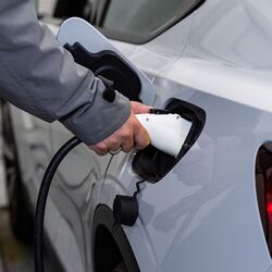 The image shows the charging process of an electric vehicle, where a charging connector is plugged into the vehicle to charge the battery during the parking process.