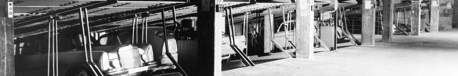 Photo en noir et blanc montrant d'anciens systèmes de stationnement dans lesquels des voitures sont garées