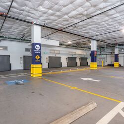 The image shows the entrance to an automated parking system in a modern underground garage with several access gates.