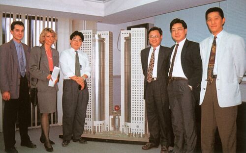 Six personnes debout devant une maquette de gratte-ciel