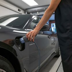 Une femme branche une prise de recharge électrique sur sa voiture
