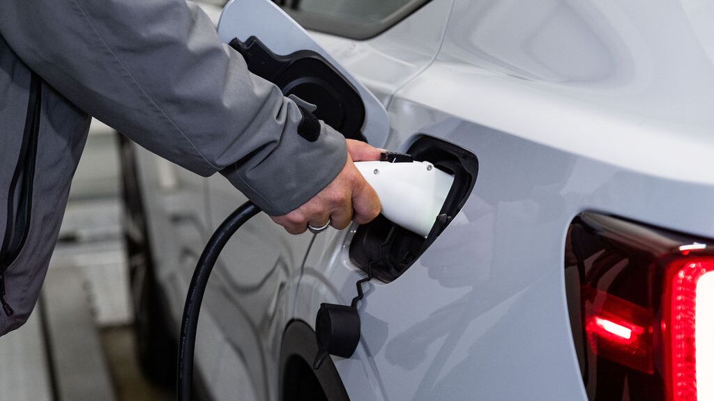 The image shows the charging process of an electric vehicle, where a charging connector is plugged into the vehicle to charge the battery during the parking process.
