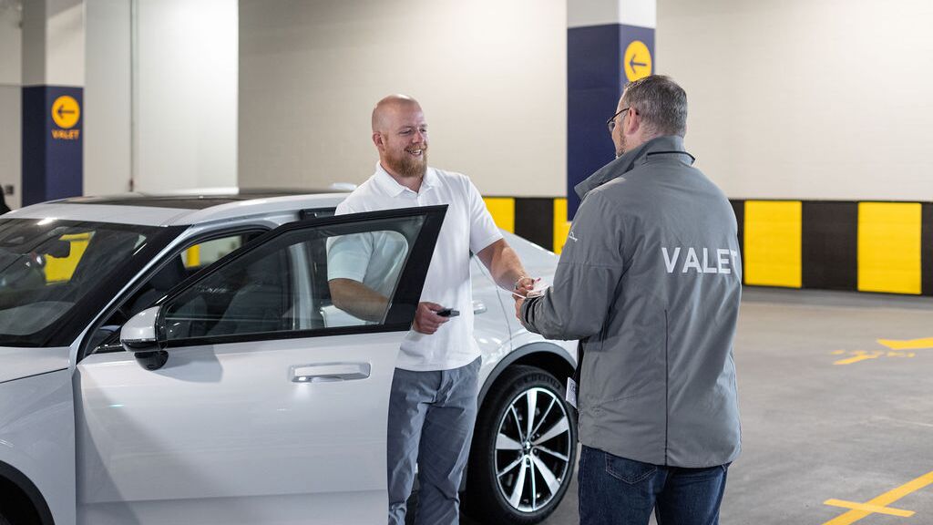 The image shows the vehicle handover in an automated parking system, where the vehicle key is handed over to the user after the vehicle has been retrieved from the parking system.