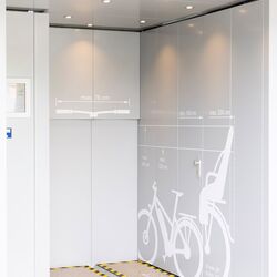 Zone d'entrée d'un parking à vélos en hauteur avec un pictogramme représentant un vélo sur le mur